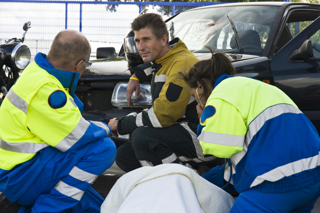 fireman and paramedic discussing the course of action, carrying for an woman ad the side of a car crash