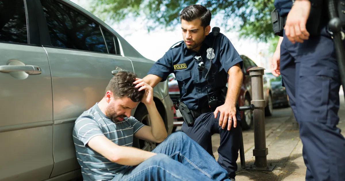 Injured young man suffering in pain after a car accident talking with the police officers