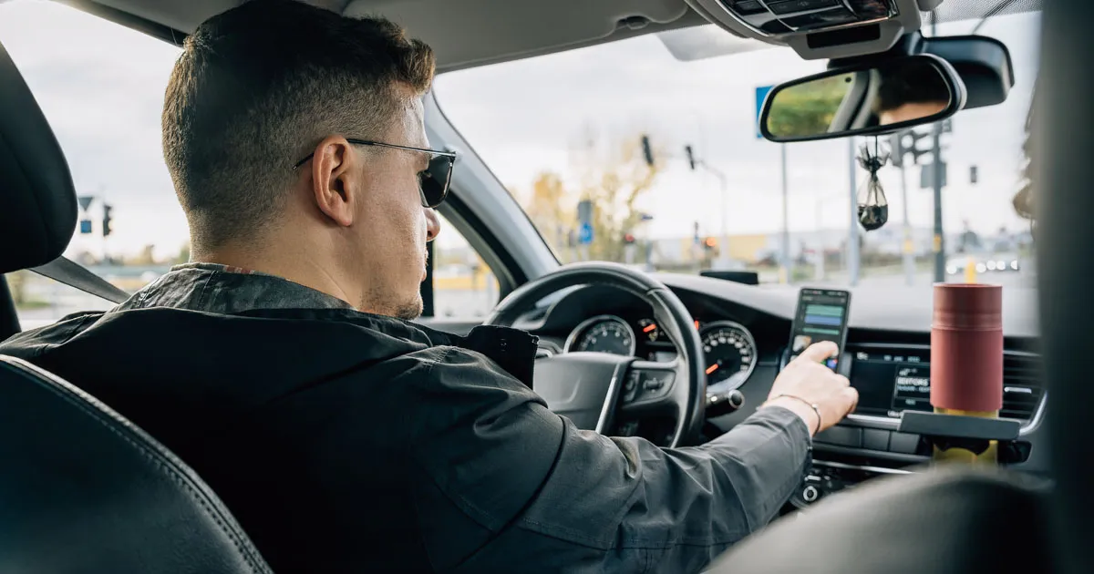 A man uses a using navigation devices while driving a car.