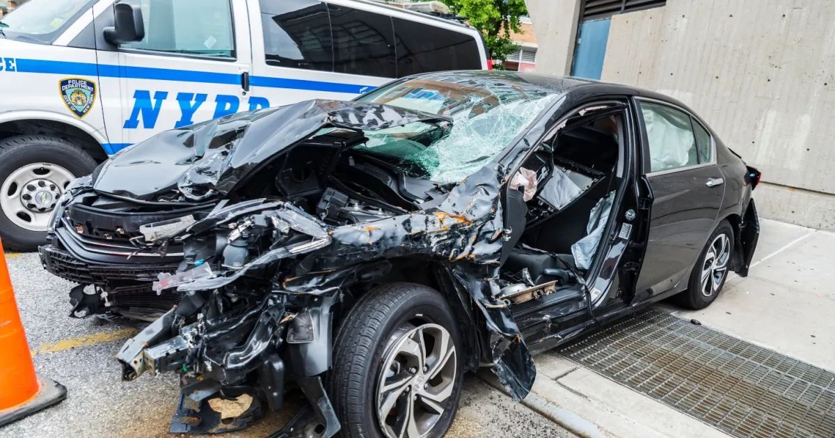 Police car and a car shattered by a crash parked on street next to a police station in Harlem, Manhattan, New York