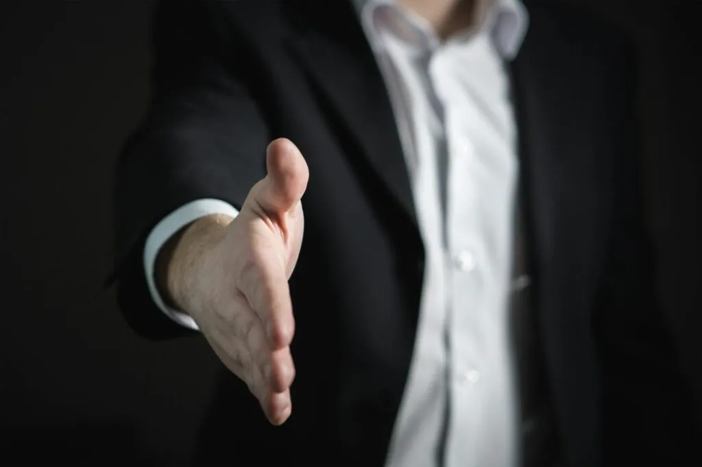 Businessman extending hand greeting dark background