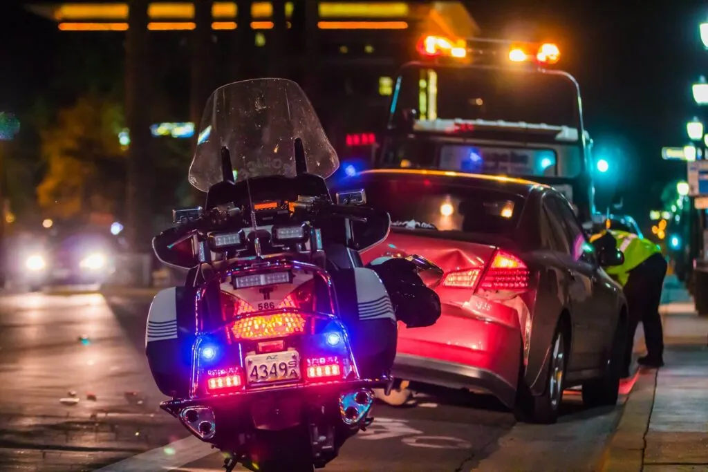 a motorcycle parked on the side of a road at night. It features the vehicle's tail and brake light