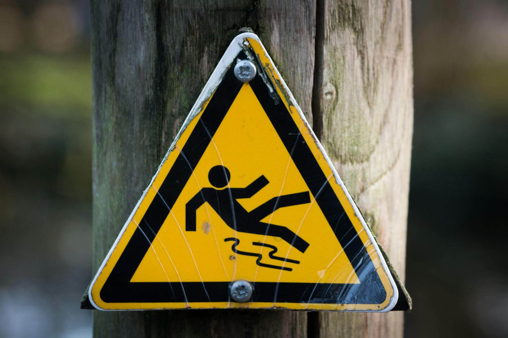 Slippery surface warning sign on wooden post