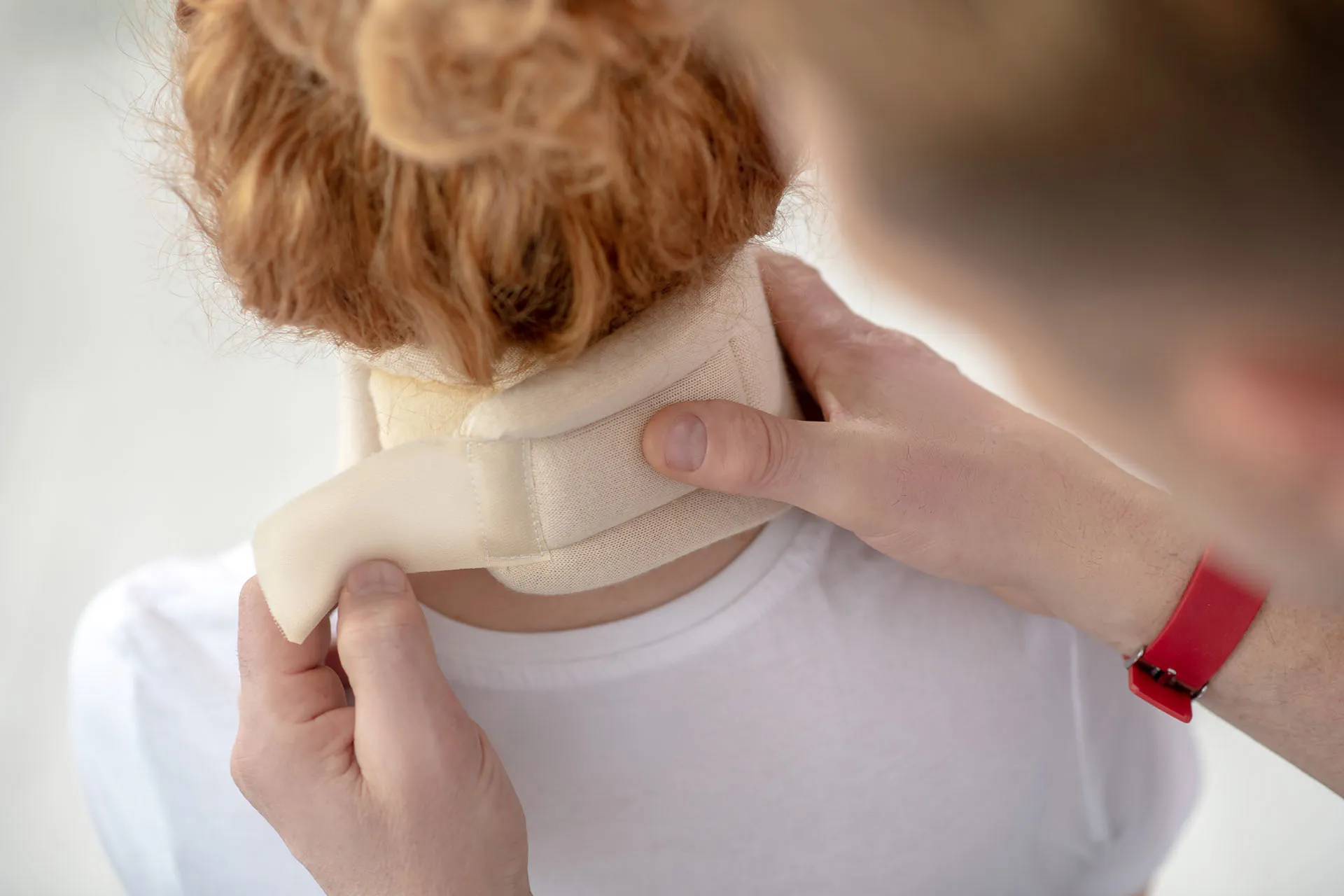 A medical professional securing a cervical collar around a person's neck.