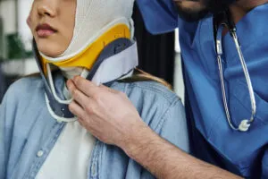 A person in medical scrubs adjusting a neck brace on a patient.