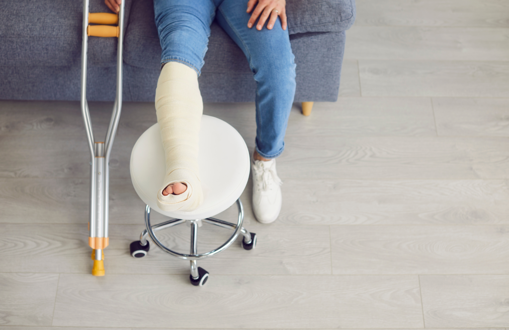 Young man with an injured leg and foot sitting on the couch at home, with his foot resting on a stool.