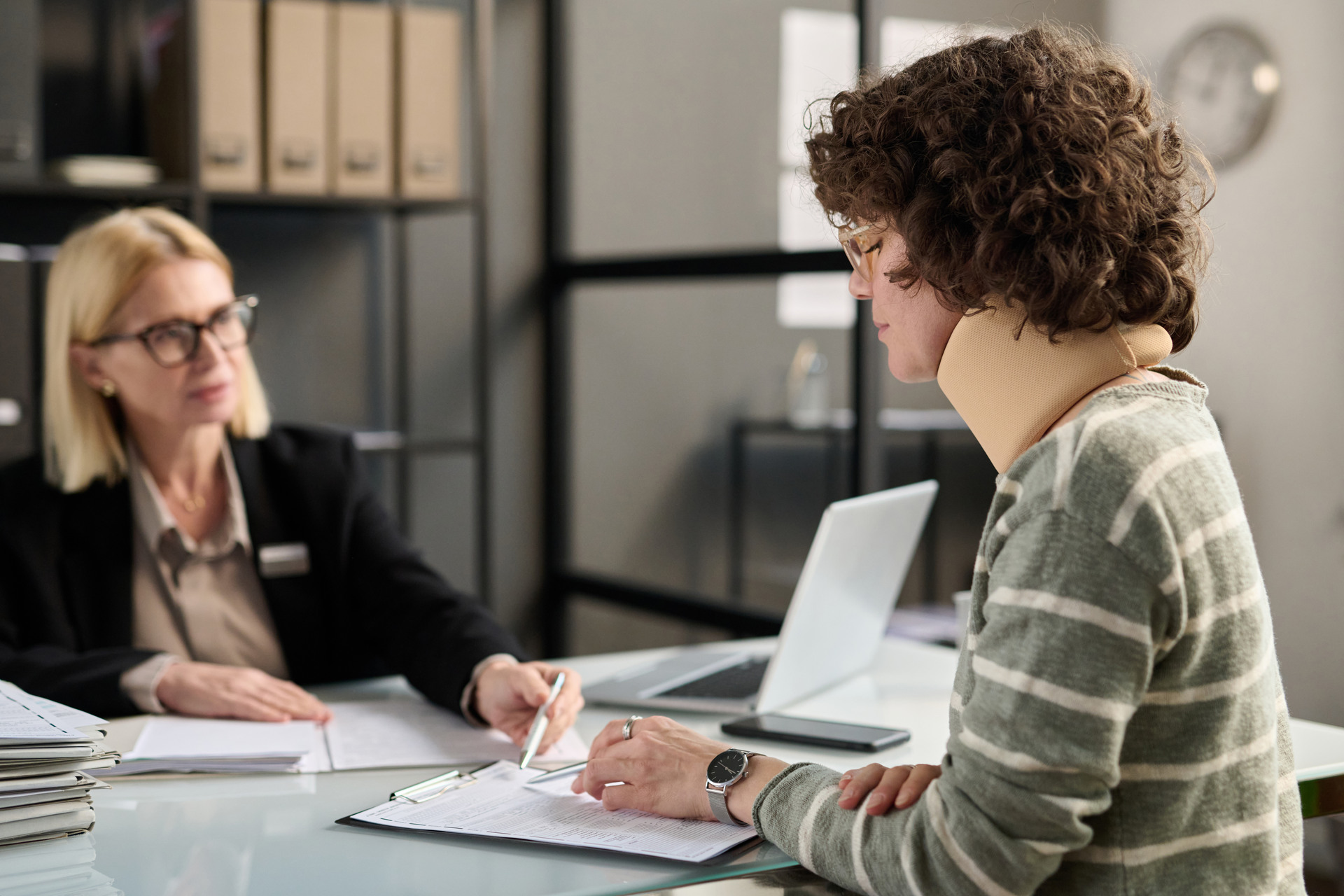 woman with neck injury filling documents with lawyer
