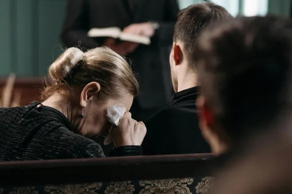 Woman wiping tears at a funeral service.