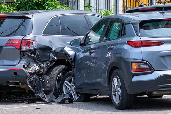 A gray SUV has rear-ended another gray vehicle, causing significant damage to the bumper and rear wheel area of the car in front, and impact damage to the front bumper of the SUV.