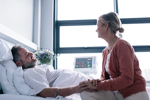 Man in hospital with wife holding hand